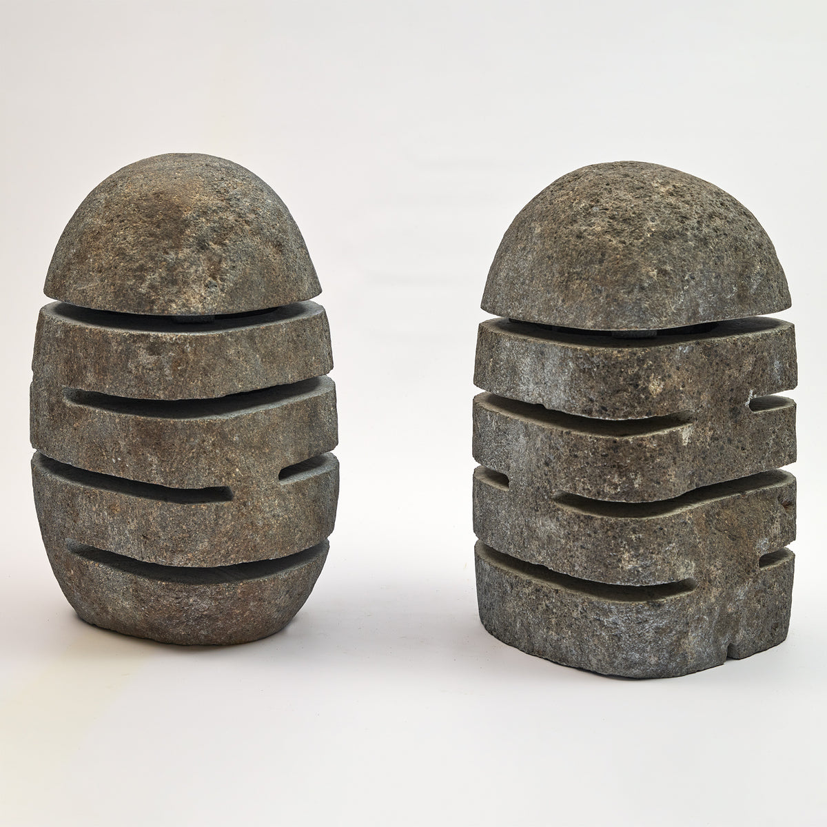 Zwei Laternen aus Naturstein mit kugeligem Deckel und Schlitzöffnungen