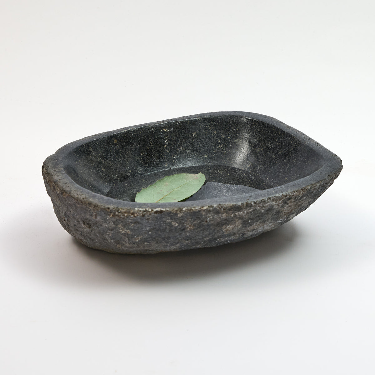 Schale aus Flussstein, kleine dunkle graue Schale mit grünem Blatt im Wasserbecken